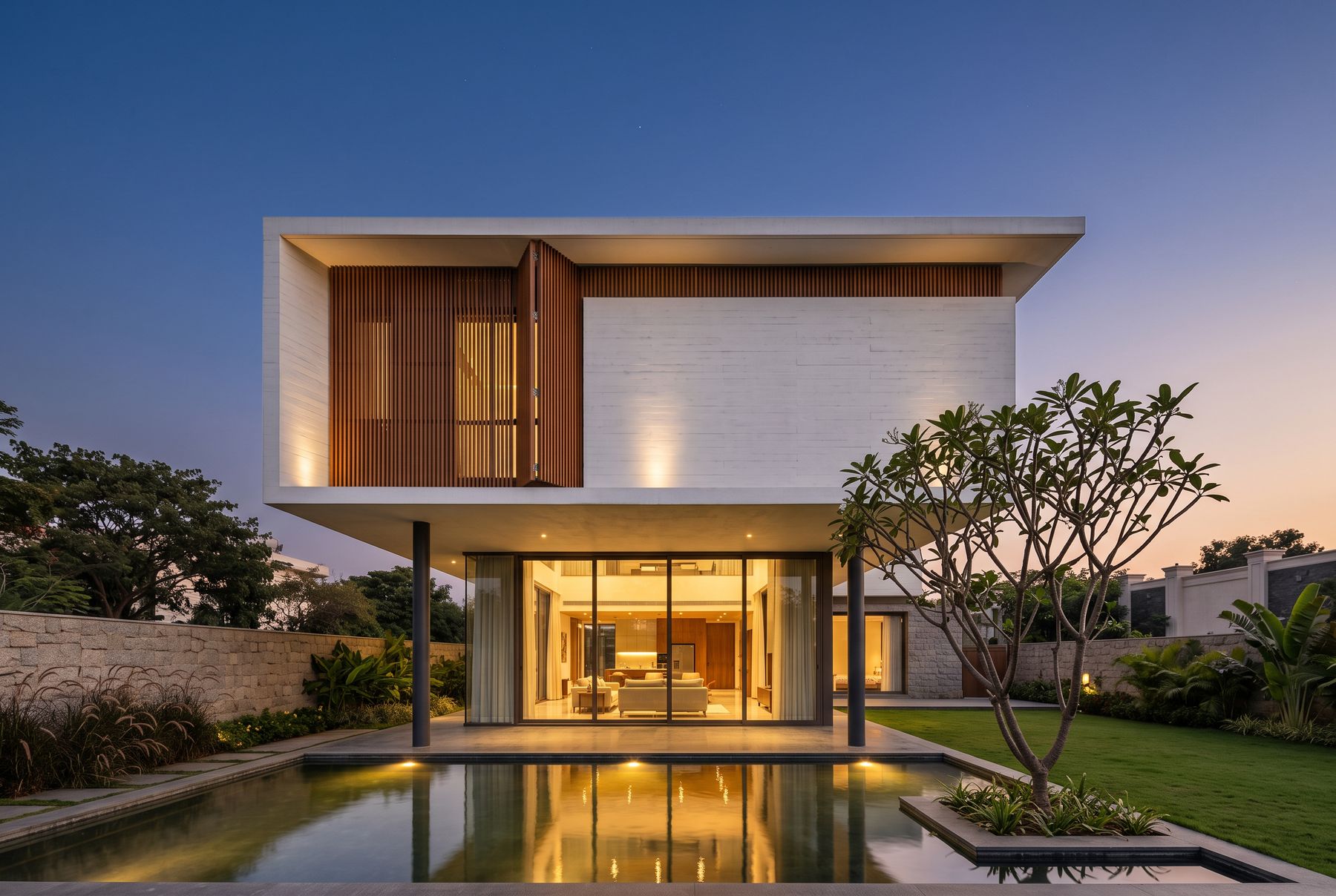 Contemporary white concrete villa at dusk, warm light glowing through glass and reflected in a pool.
